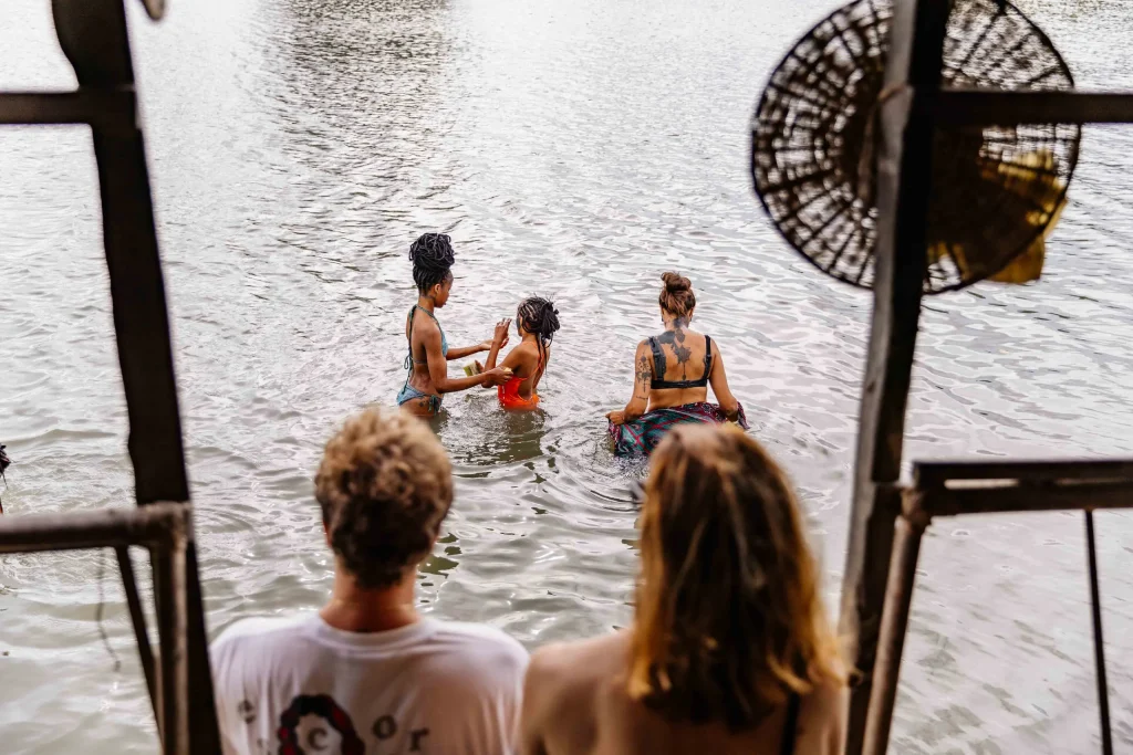 Une femme et deux enfants se rincent dans l’eau calme du lac, tandis que deux personnes les regardent depuis un ponton